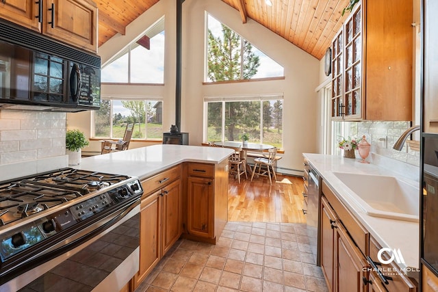 kitchen with appliances with stainless steel finishes, wooden ceiling, a sink, light countertops, and backsplash