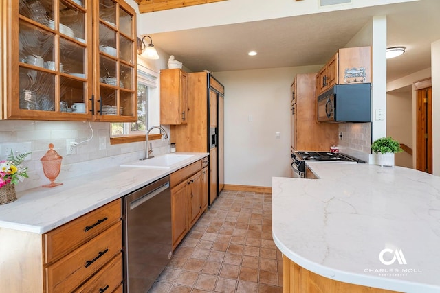 kitchen featuring a sink, stainless steel appliances, tasteful backsplash, light stone finish flooring, and light stone countertops