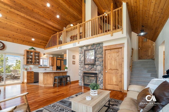 living room with high vaulted ceiling, wood ceiling, stairs, light wood finished floors, and a fireplace