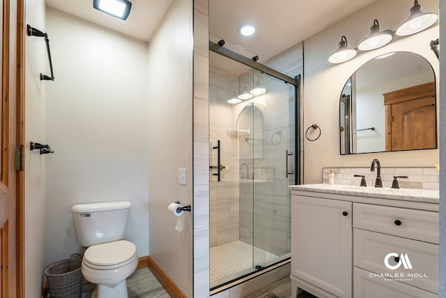full bath with a shower stall, toilet, vanity, and baseboards