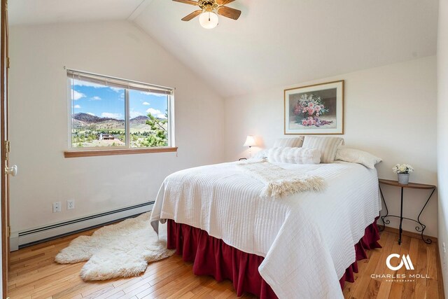 bedroom featuring a baseboard radiator, wood finished floors, vaulted ceiling, and ceiling fan