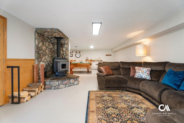 living area with a wood stove, concrete flooring, and a wainscoted wall