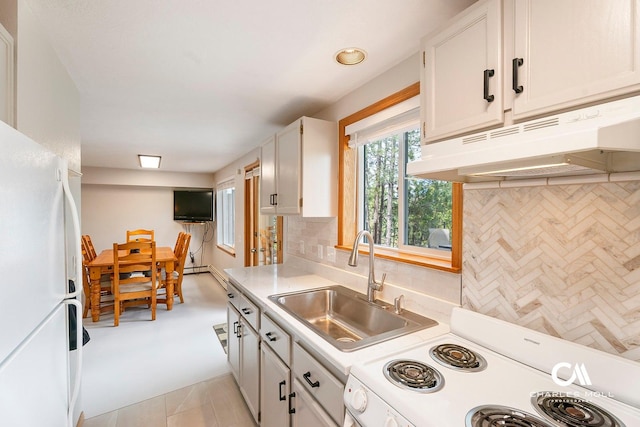 kitchen with white appliances, under cabinet range hood, a sink, light countertops, and tasteful backsplash