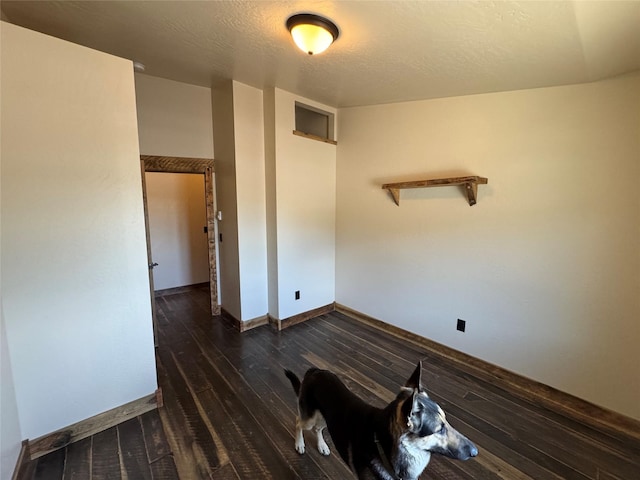 spare room with hardwood / wood-style floors, baseboards, and a textured ceiling
