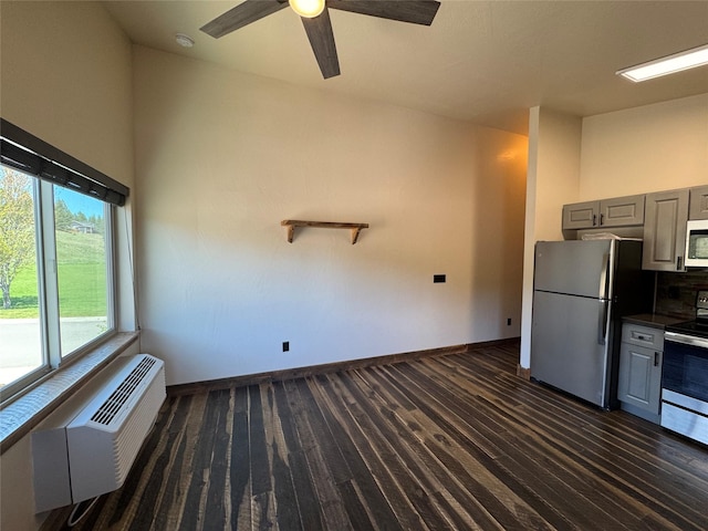 kitchen with appliances with stainless steel finishes, gray cabinets, dark wood-style flooring, dark countertops, and a ceiling fan