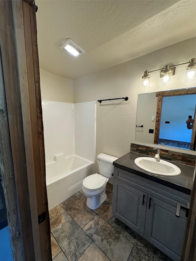 full bathroom featuring toilet, vanity, a textured ceiling, a textured wall, and washtub / shower combination