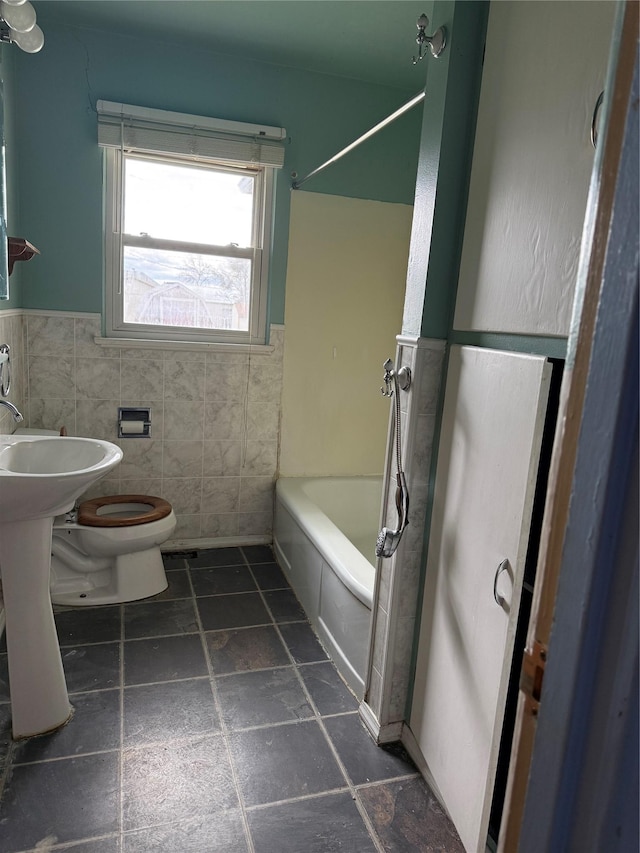 full bath featuring toilet, tile walls, wainscoting, and shower / bathtub combination