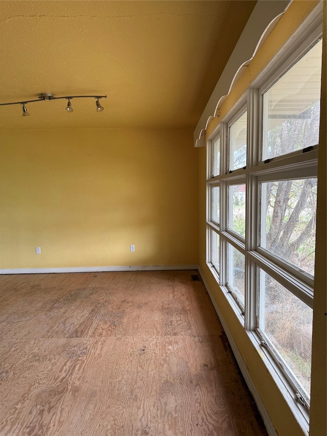 empty room featuring baseboards and rail lighting