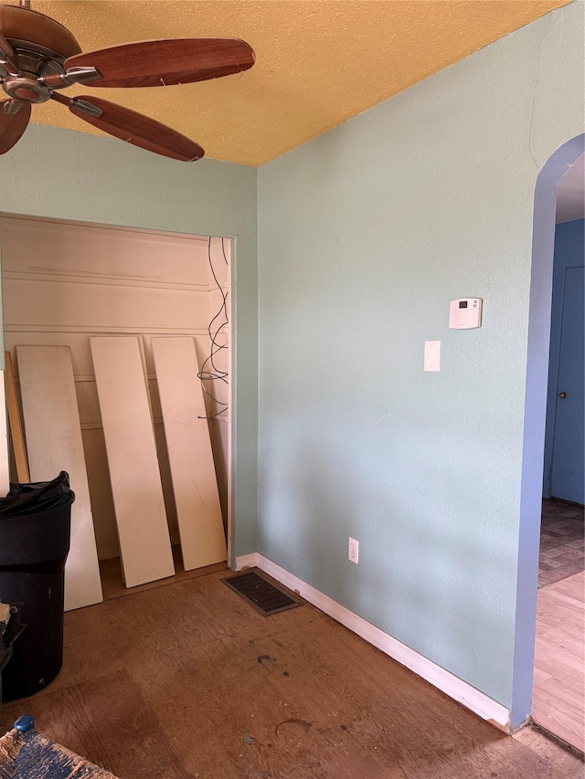 unfurnished bedroom featuring arched walkways, a closet, ceiling fan, and wood finished floors