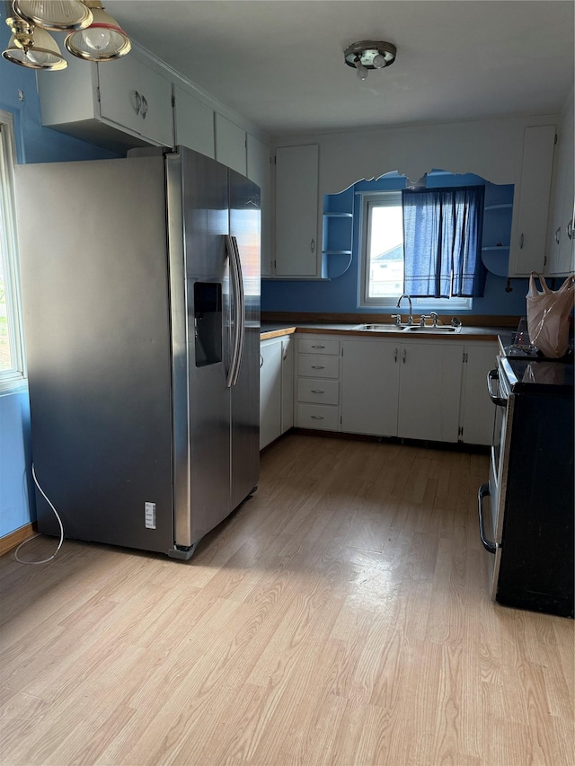 kitchen with stainless steel appliances, a sink, light wood-style floors, and open shelves
