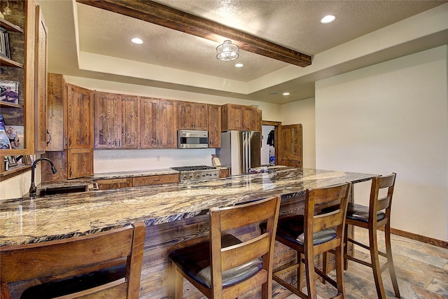 45292 Locust Ln, Charlo, MT 59824 - kitchen featuring stainless steel appliances, a sink, a breakfast bar area, baseboards, and stone tile floors