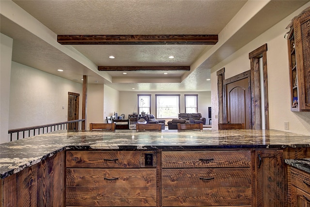 45292 Locust Ln, Charlo, MT 59824 - kitchen with dark stone countertops, a textured ceiling, recessed lighting, open floor plan, and beam ceiling