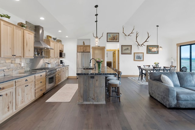 559 Stage Springs Ln, Stevensville, MT 59870 - kitchen with wall chimney exhaust hood, appliances with stainless steel finishes, light brown cabinets, a kitchen breakfast bar, and tasteful backsplash