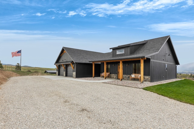 559 Stage Springs Ln, Stevensville, MT 59870 - modern inspired farmhouse with gravel driveway, stone siding, a garage, roof with shingles, and covered porch