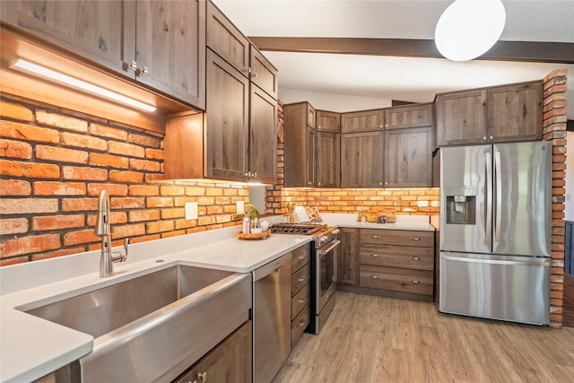kitchen featuring appliances with stainless steel finishes, a sink, beam ceiling, light wood-type flooring, and light countertops