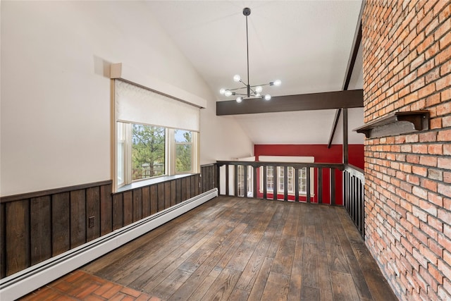 spare room featuring a baseboard heating unit, vaulted ceiling, wainscoting, hardwood / wood-style floors, and a chandelier