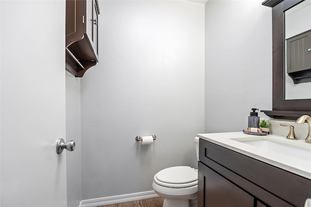 bathroom featuring wood finished floors, toilet, vanity, and baseboards
