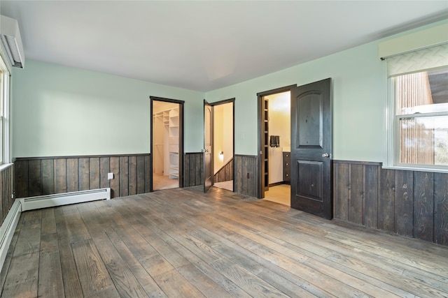 spare room featuring a wainscoted wall, hardwood / wood-style flooring, a baseboard heating unit, and wooden walls
