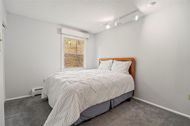 carpeted bedroom featuring a baseboard radiator, rail lighting, a textured ceiling, and baseboards
