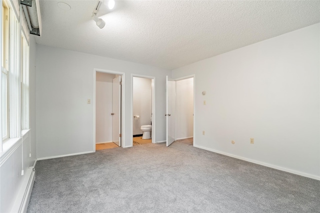 unfurnished bedroom featuring a baseboard radiator, light carpet, ensuite bath, and baseboards