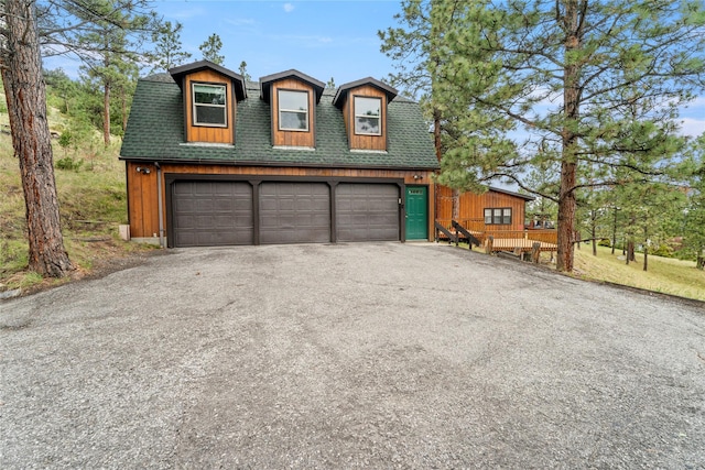 view of front facade with roof with shingles and a garage