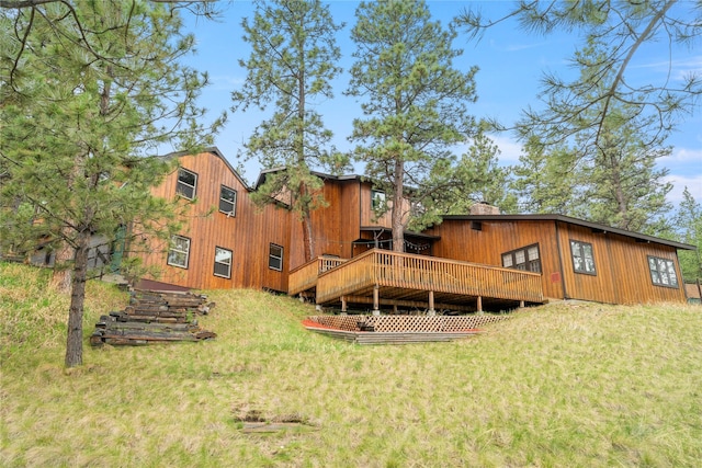 rear view of property featuring a lawn and a deck