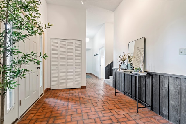 hallway featuring brick flooring, a towering ceiling, and stairway