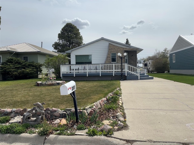 307 S Iowa St, Conrad, MT 59425 - view of front of house featuring stone siding, a front lawn, and a wooden deck