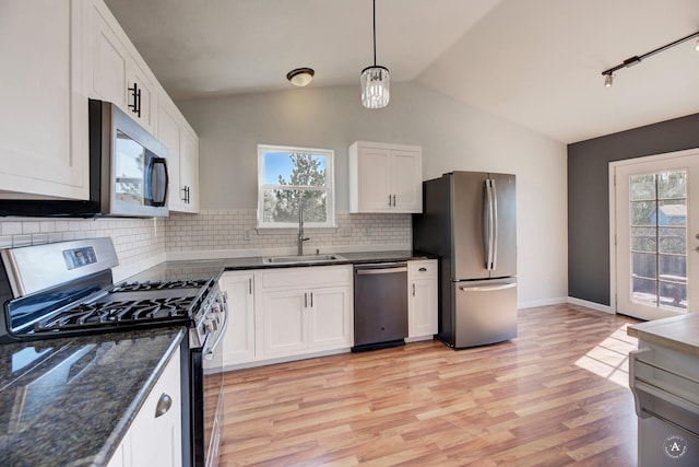kitchen featuring stainless steel appliances, a sink, lofted ceiling, plenty of natural light, and light wood-style floors