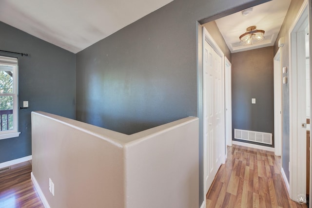 hall with an upstairs landing, wood finished floors, baseboards, and vaulted ceiling