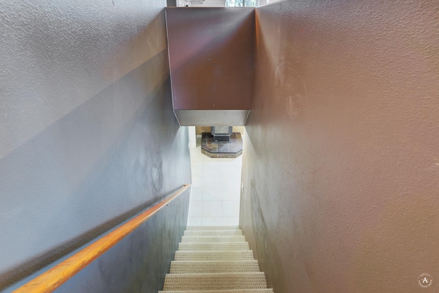 staircase featuring a textured ceiling, a textured wall, and water heater