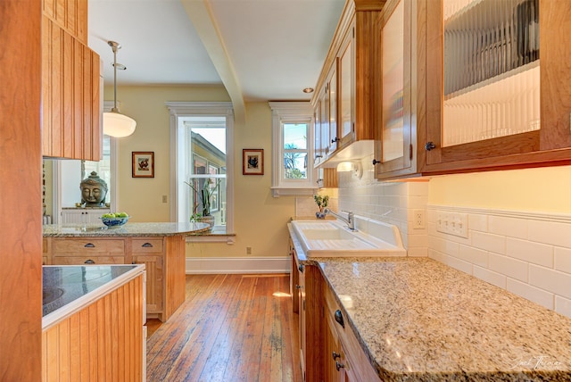 kitchen with light wood-type flooring, tasteful backsplash, baseboards, and a sink