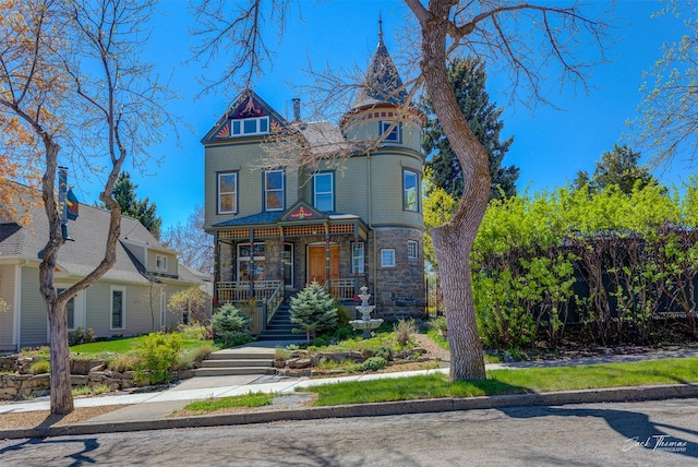 victorian home with a porch, stairs, and stone siding