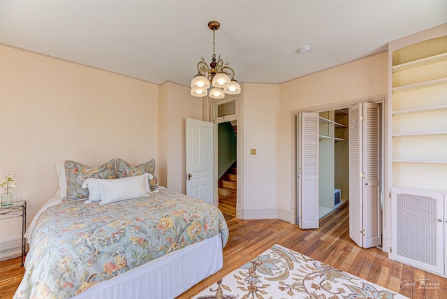 bedroom featuring wallpapered walls, radiator heating unit, wood finished floors, a chandelier, and baseboards