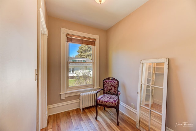 living area with radiator, wood-type flooring, and baseboards