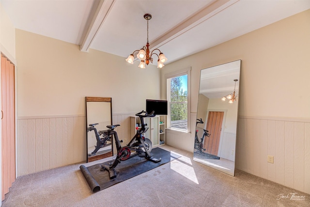 exercise area with a chandelier, wainscoting, carpet flooring, and wooden walls
