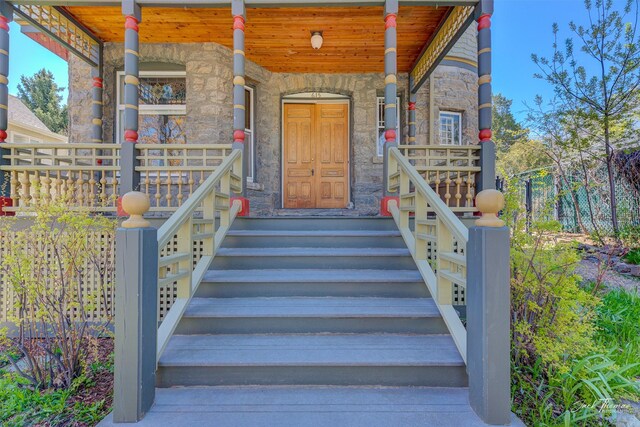 doorway to property with stone siding and a porch
