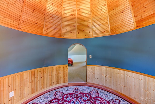 hallway featuring vaulted ceiling, arched walkways, and carpet floors