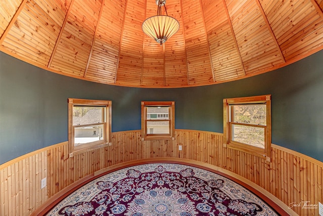 spare room featuring a wainscoted wall, wooden walls, high vaulted ceiling, and wood ceiling