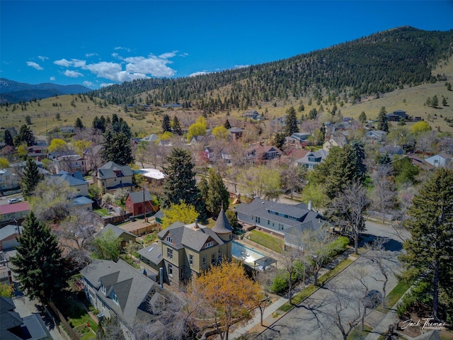 aerial view of property's location featuring nearby suburban area, a forest, and mountains
