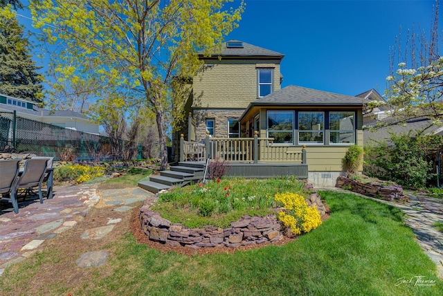 back of house featuring a wooden deck, a patio area, roof with shingles, and stone siding