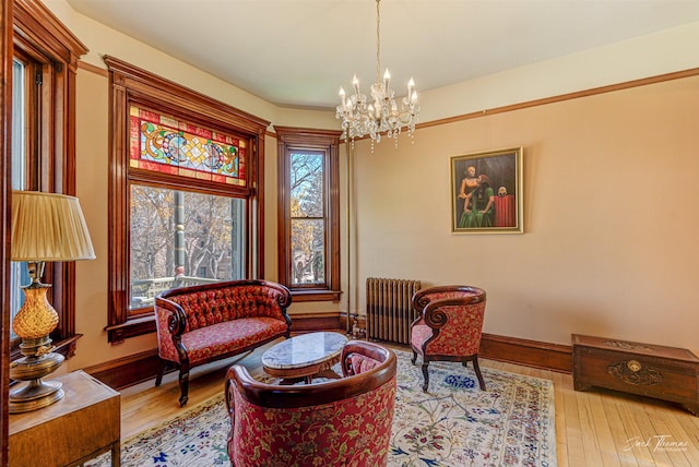 sitting room featuring radiator, a chandelier, wood finished floors, and baseboards