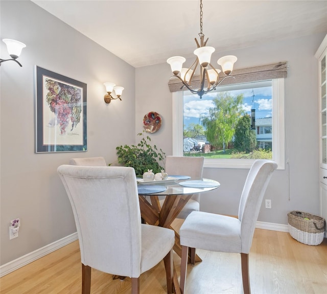 dining space featuring a chandelier, light wood-type flooring, and baseboards