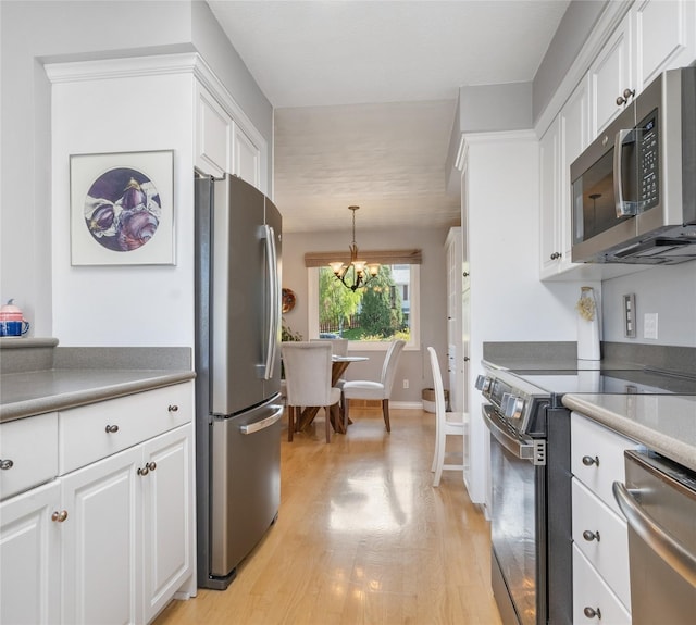 kitchen featuring stainless steel appliances, a chandelier, white cabinetry, and light wood-style flooring
