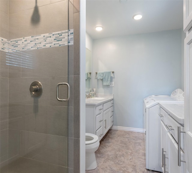 bathroom featuring separate washer and dryer, two vanities, a stall shower, toilet, and baseboards