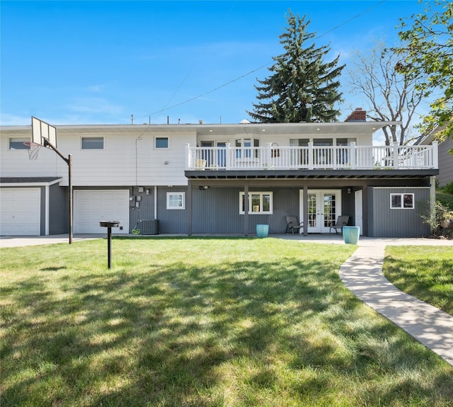 rear view of house with french doors, an attached garage, a yard, and a wooden deck