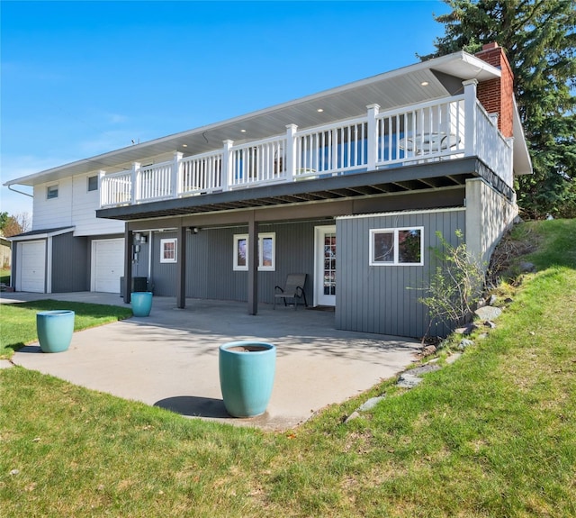 back of property with a garage, a yard, a patio, a chimney, and a wooden deck