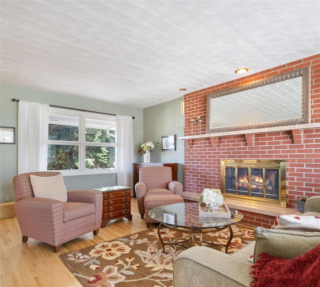 living area with a brick fireplace and wood finished floors