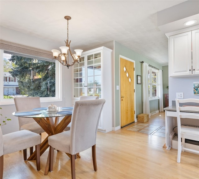 dining area with a chandelier, light wood-type flooring, and baseboards