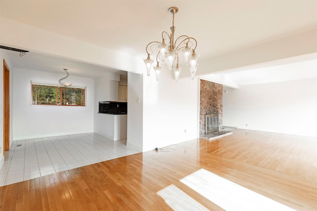 411 W River Rd, Hamilton, MT 59840 - empty room with a chandelier, wood finished floors, a stone fireplace, and baseboards